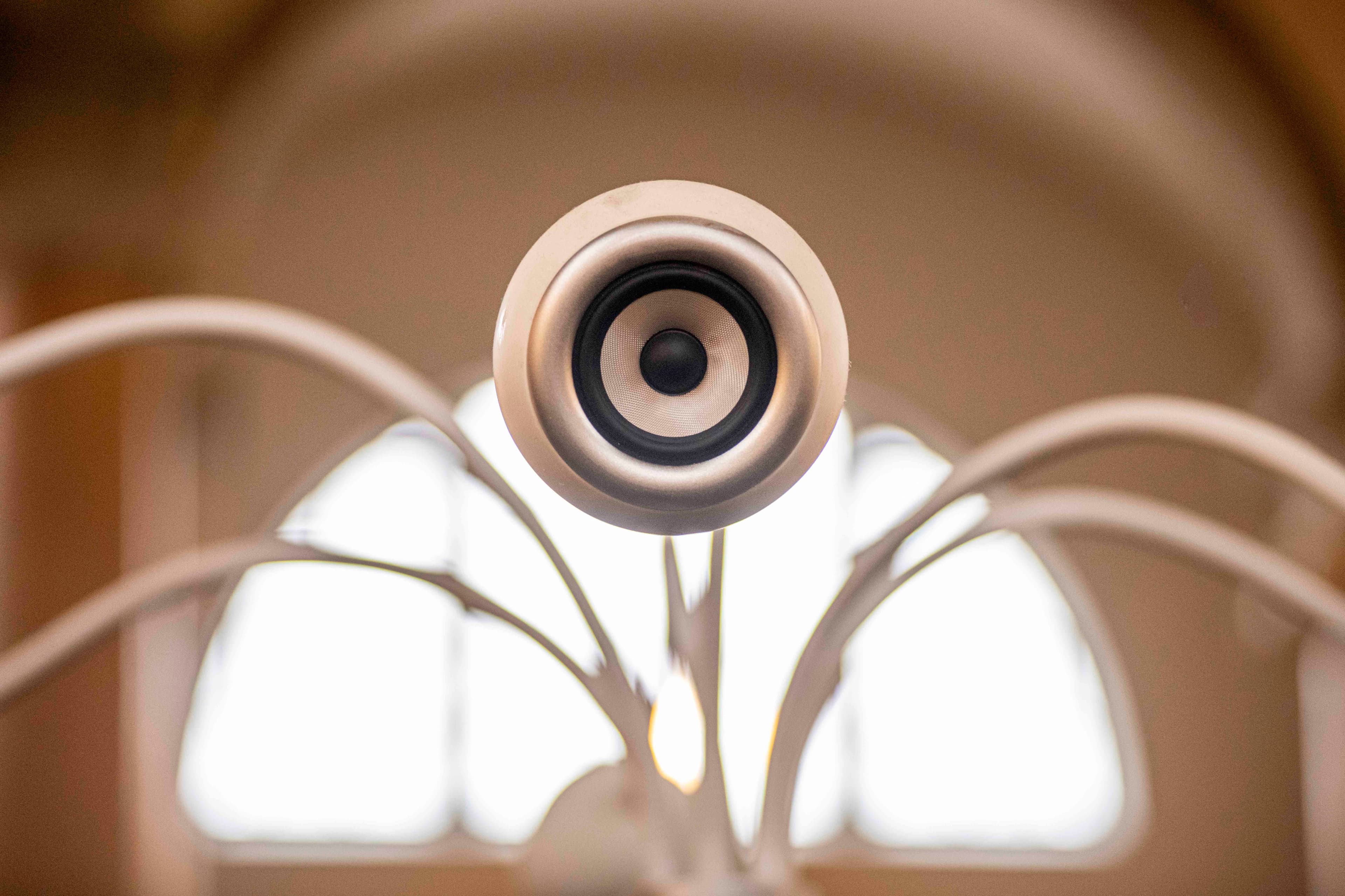 A close-up view of a modern speaker mounted on a decorative structure with a blurred background.