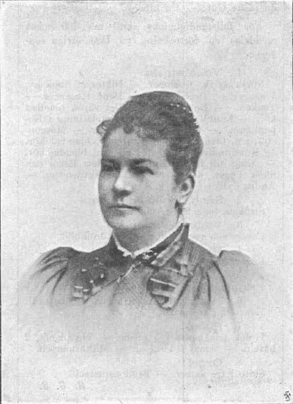 A woman in 19th-century attire with an updo hairstyle and a high-collared dress gazes to the side.